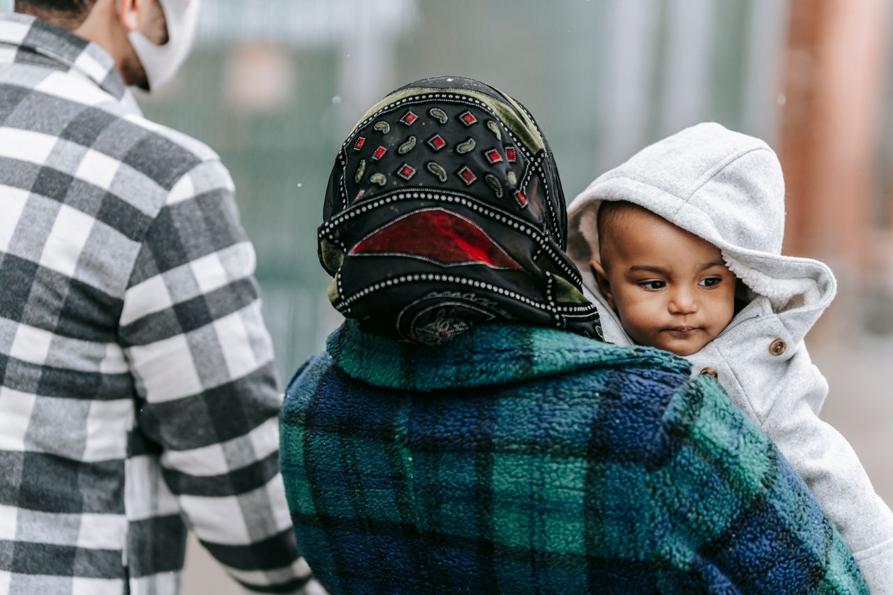 why-choose-us-01 Anonymous father and mother with African American baby in warm outerwear on hands walking on street in city on blurred background